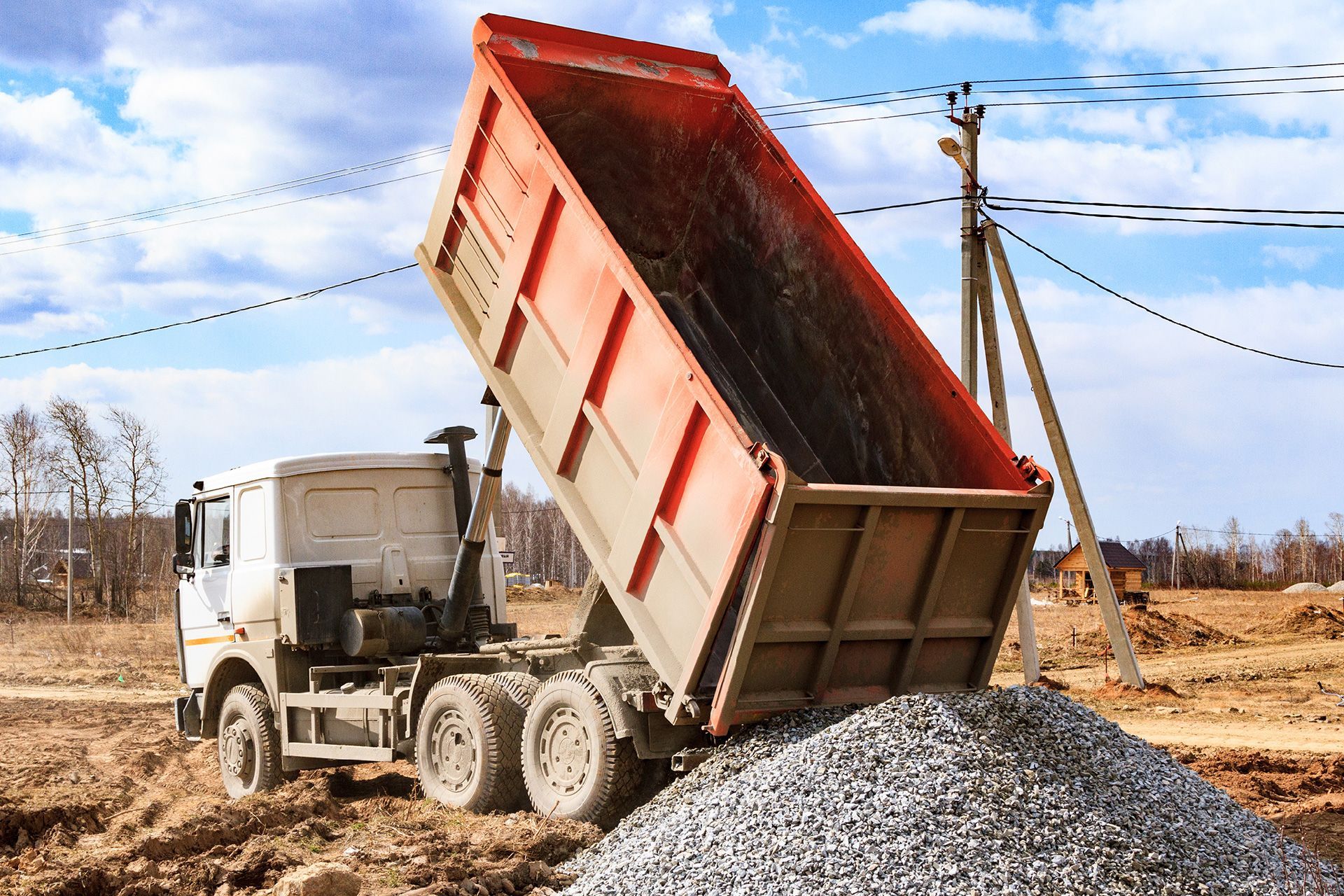 Un camión volquete está vertiendo grava encima de una pila de grava.