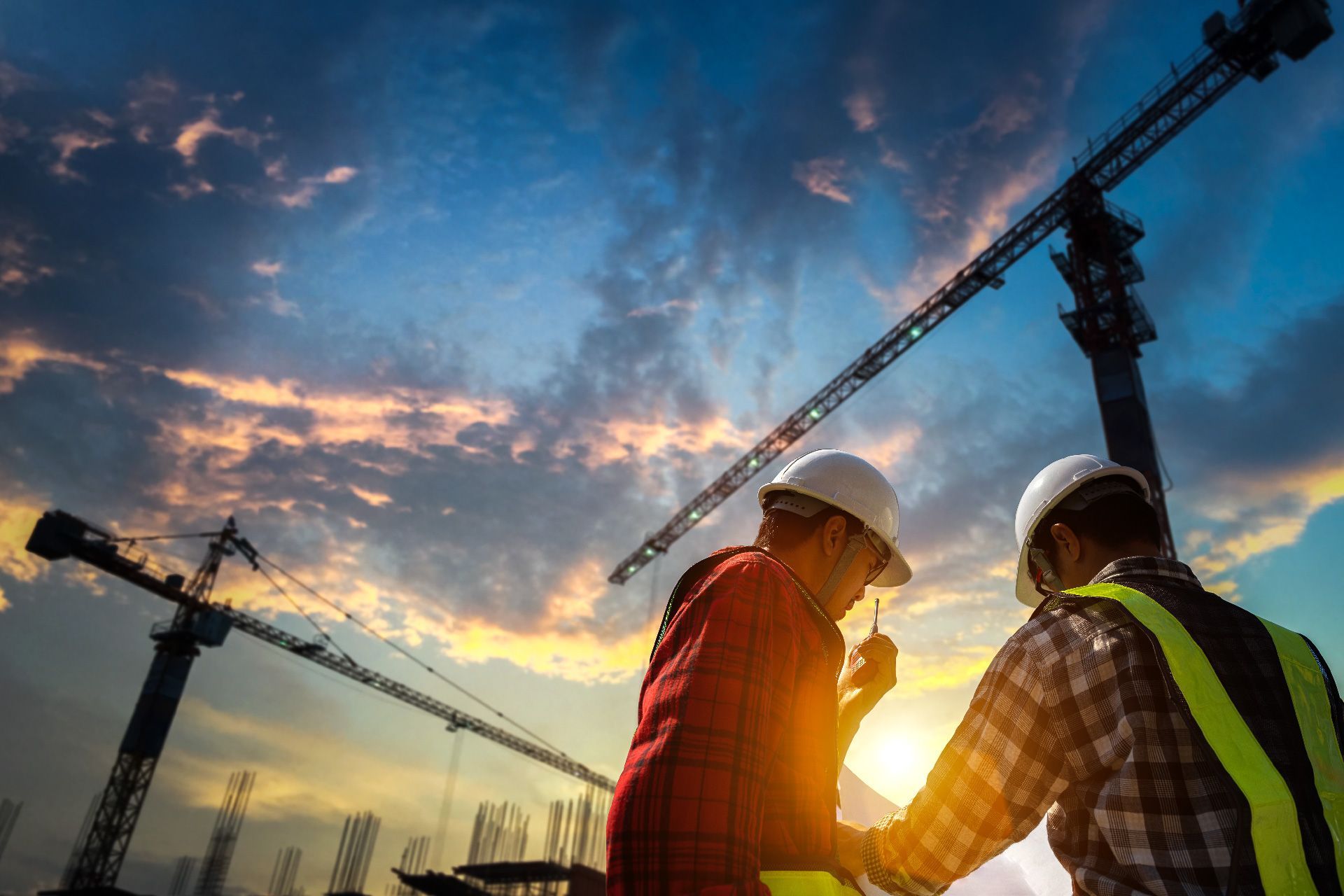 Dos trabajadores de la construcción están mirando un plano en un sitio de construcción.