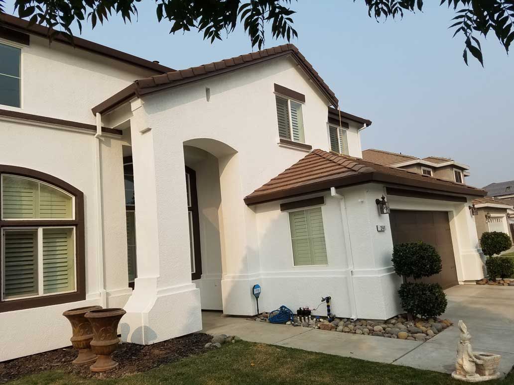 A white house with a brown roof and a lot of windows