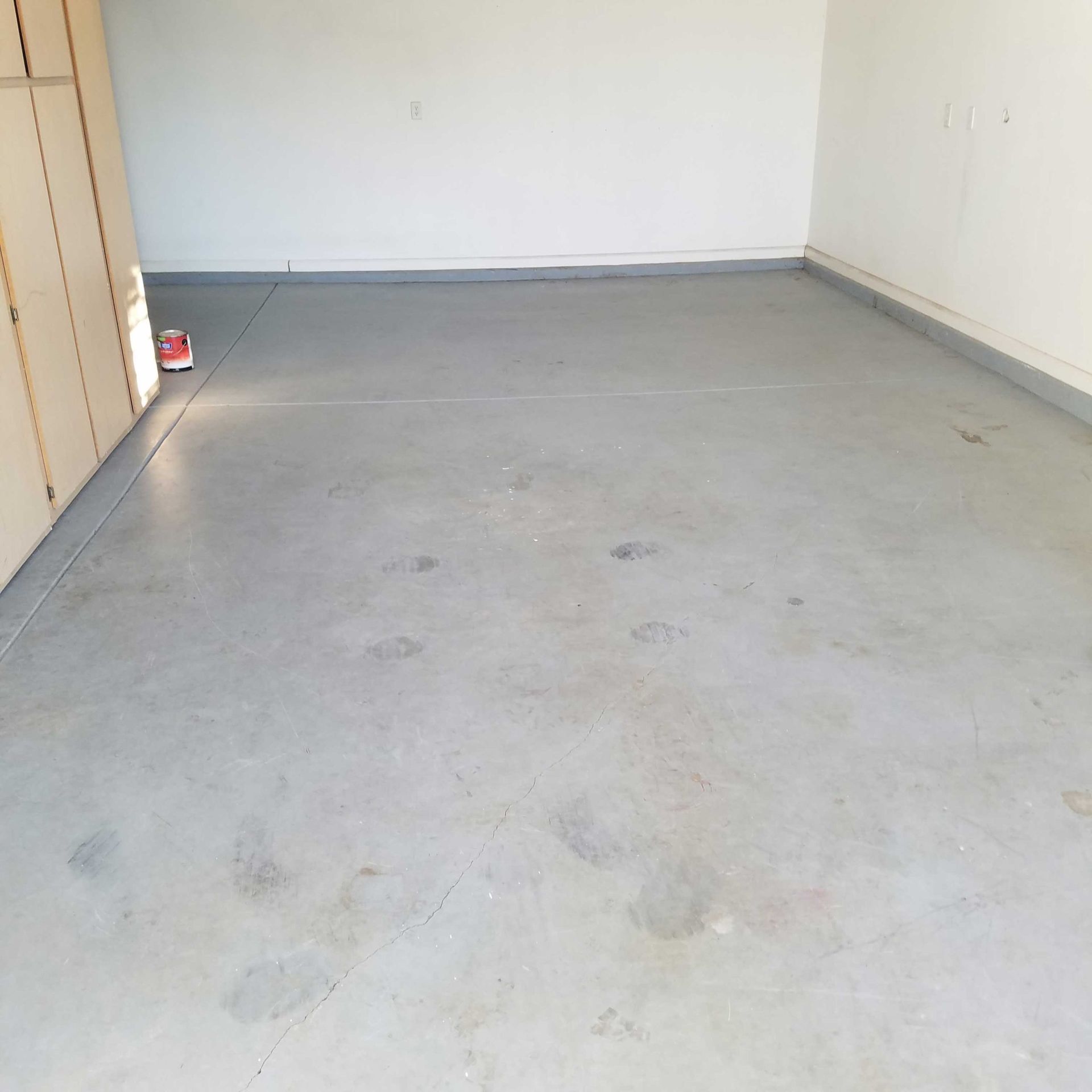 A gray concrete floor in a garage with white walls.