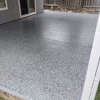 A gray concrete patio with a white fence in the background.