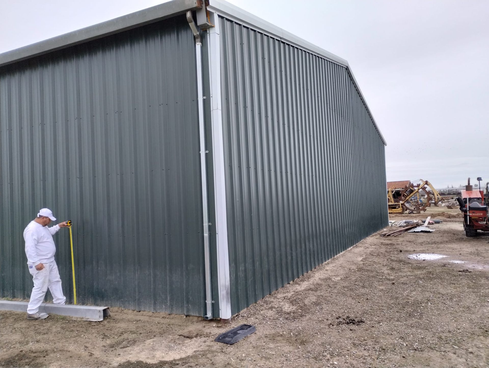 A man is measuring the side of a building with a tape measure.