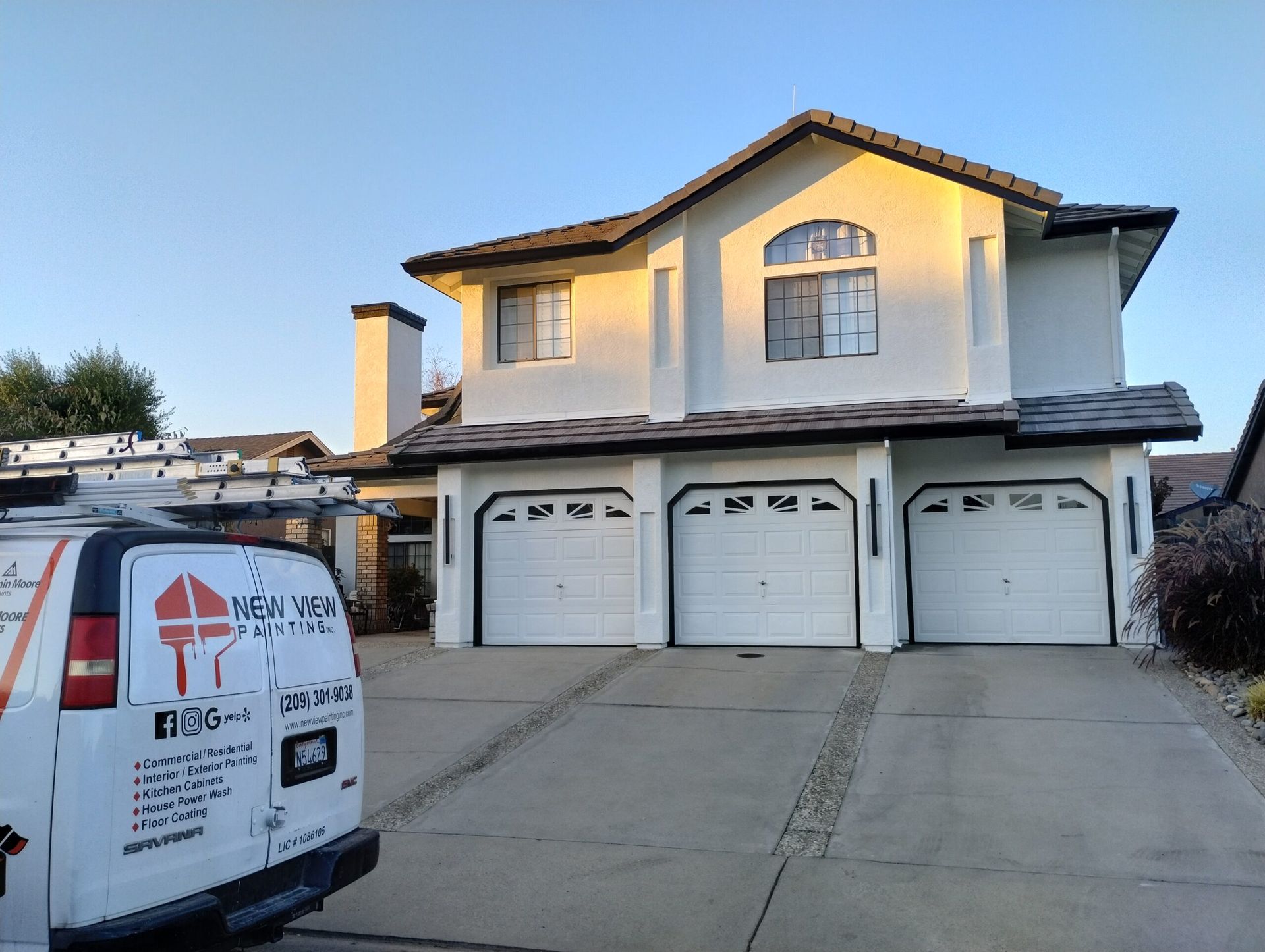 A wooden fence is being painted in a backyard.