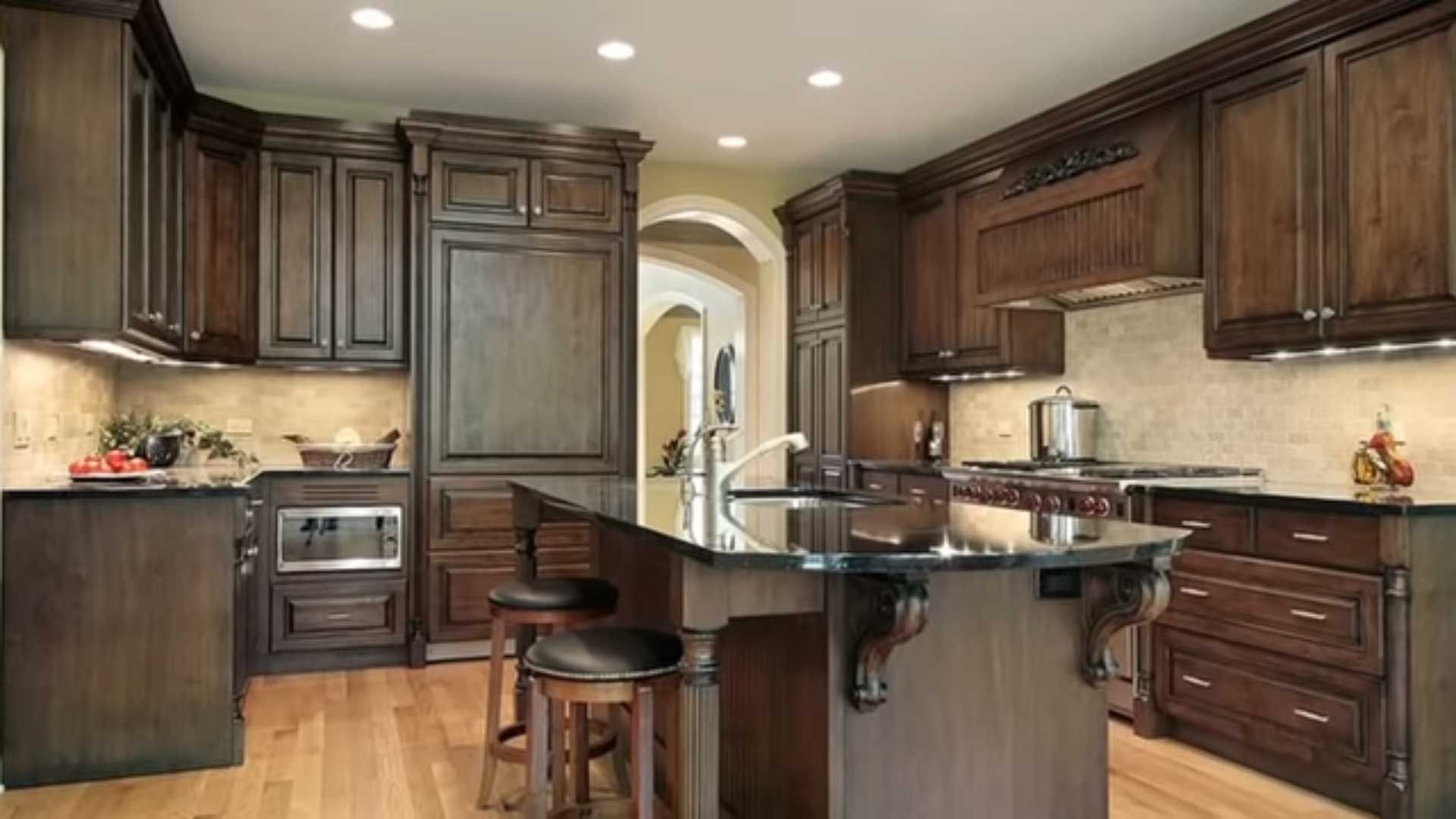 A kitchen with wooden cabinets , granite counter tops , and a large island.