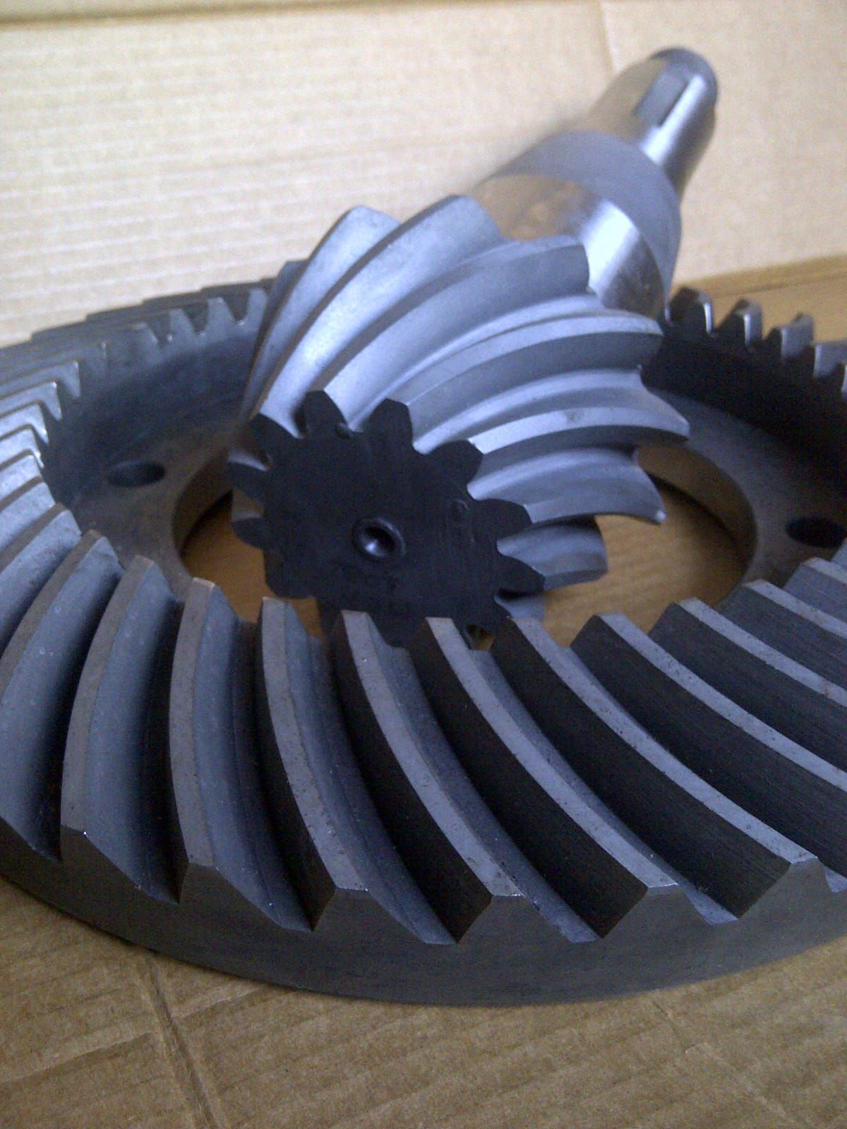 Primer plano de un conjunto de engranajes diferenciales de metal oscuro: un engranaje anular grande y un engranaje de piñón.