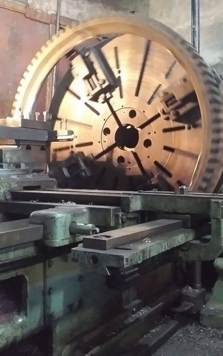 Un engranaje metálico de gran tamaño en el que se trabaja con un torno en un taller.