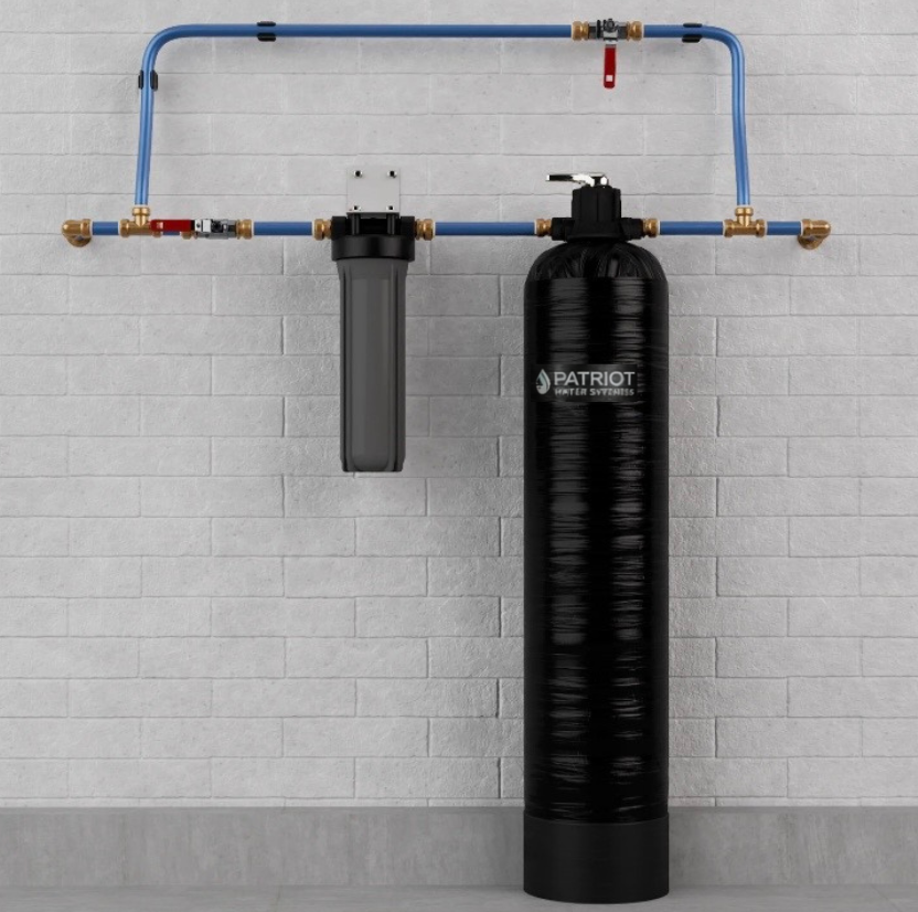 Water filtration system featuring a sediment filter and a large black tank connected by blue pipes against a white wall.