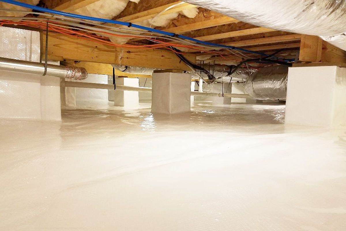 Crawl space with white vapor barrier, support beams, ductwork, and electrical wiring.