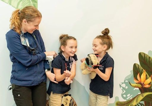 A woman is standing next to two little girls holding stuffed animals. Asheville Pediatric Dentistry (828) 277-6788