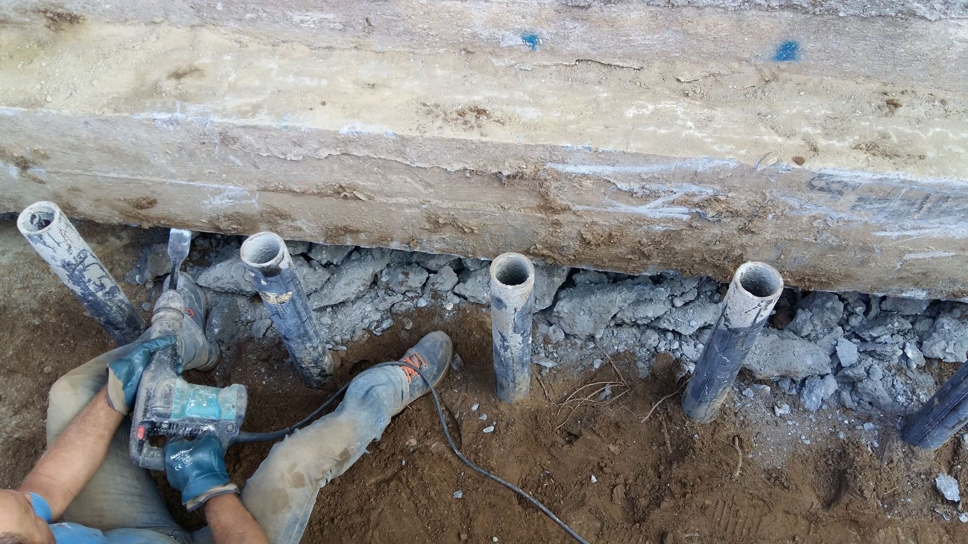 Una persona sta usando un trapano per praticare dei fori nel terreno.