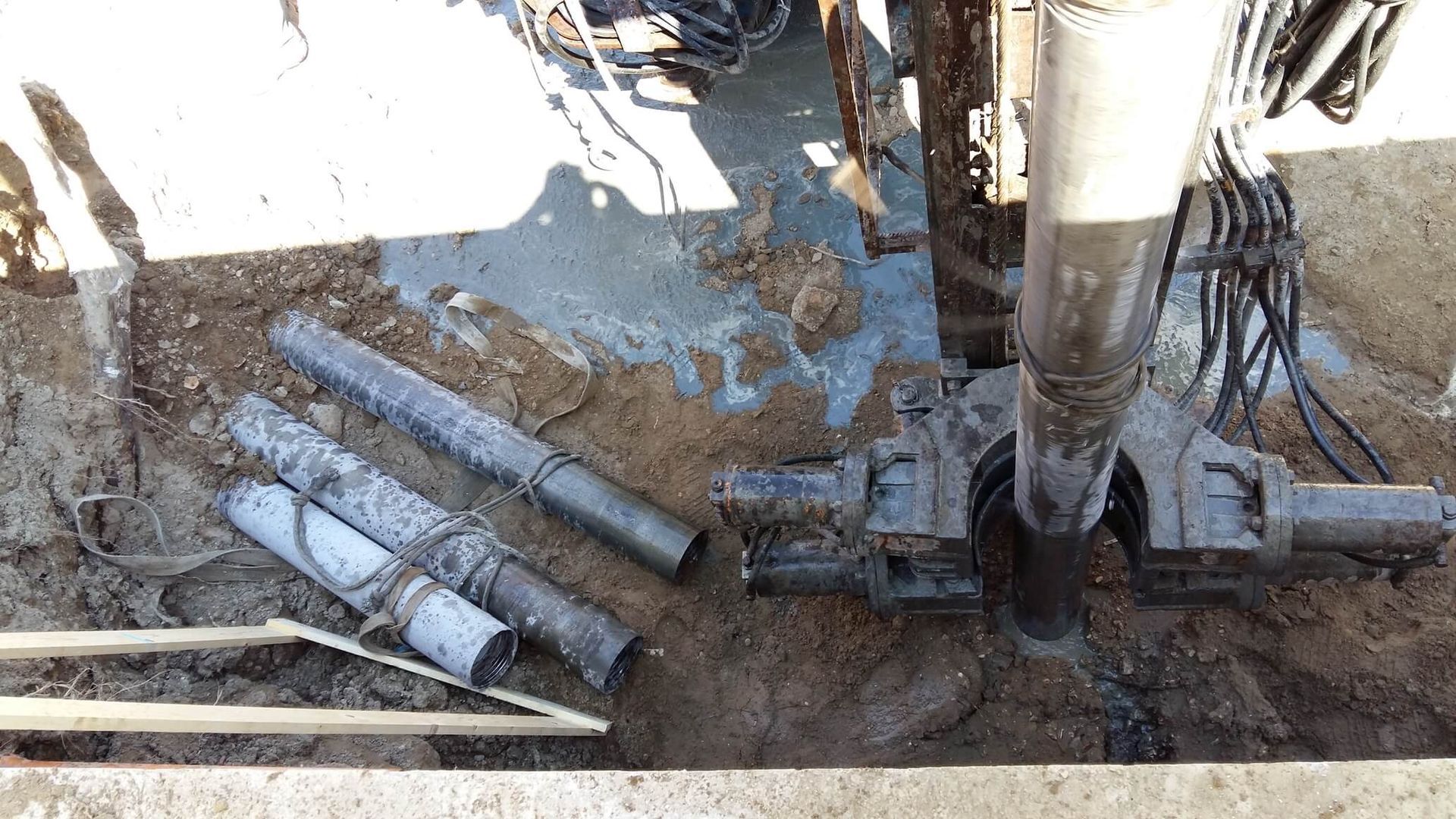 Un mucchio di tubi giace a terra accanto a una macchina.