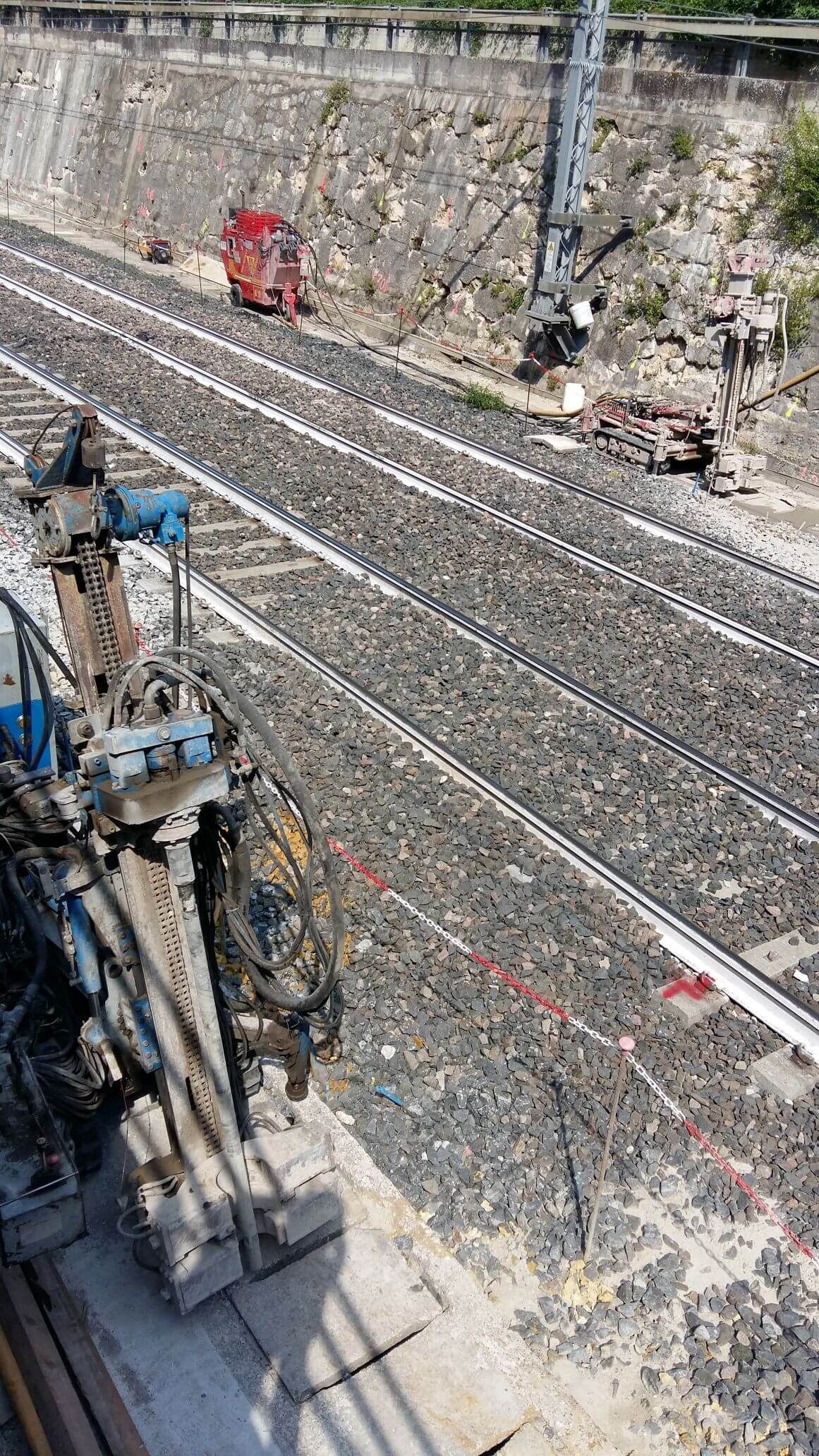 Un treno procede lungo i binari accanto a un muro.