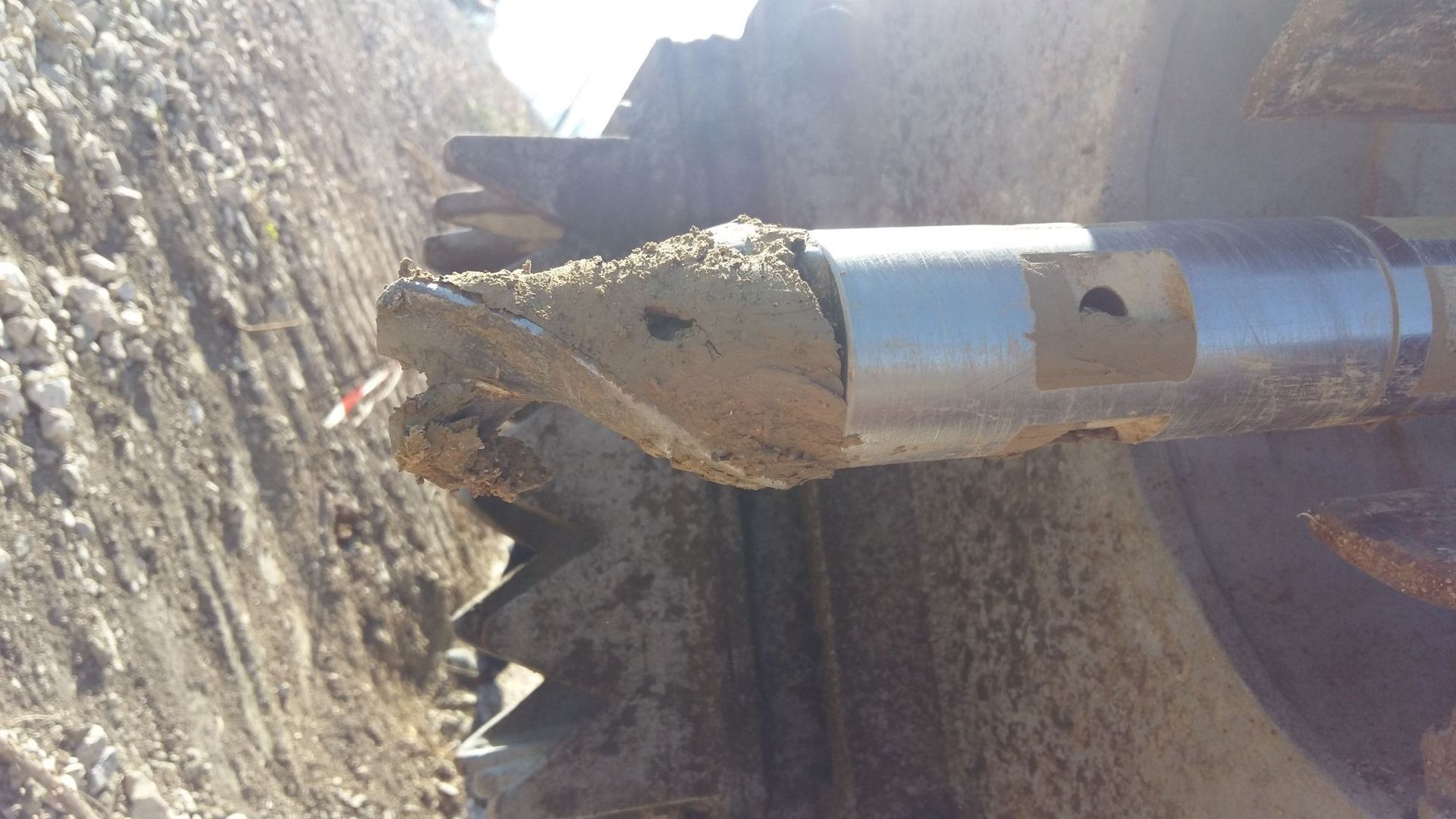 Un grande oggetto metallico è appoggiato nella terra vicino a un muro.