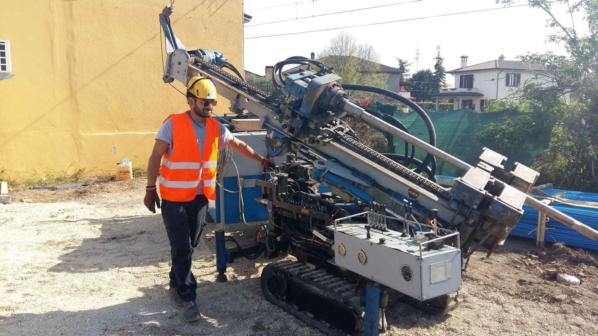 Un uomo con un giubbotto arancione è in piedi accanto a una macchina per il consolidamento dei tracciati ferroviari