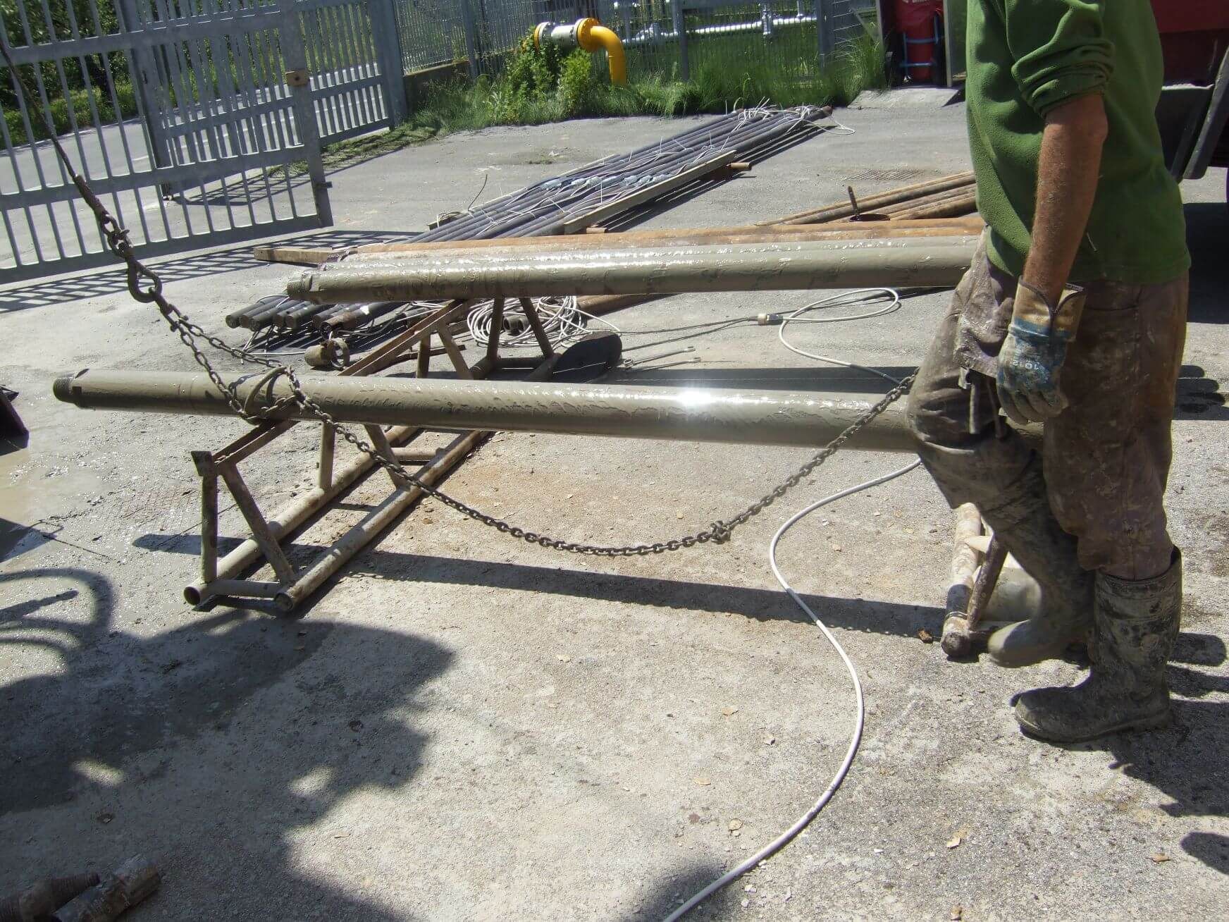 Un uomo con una camicia verde tiene in mano un palo di metallo