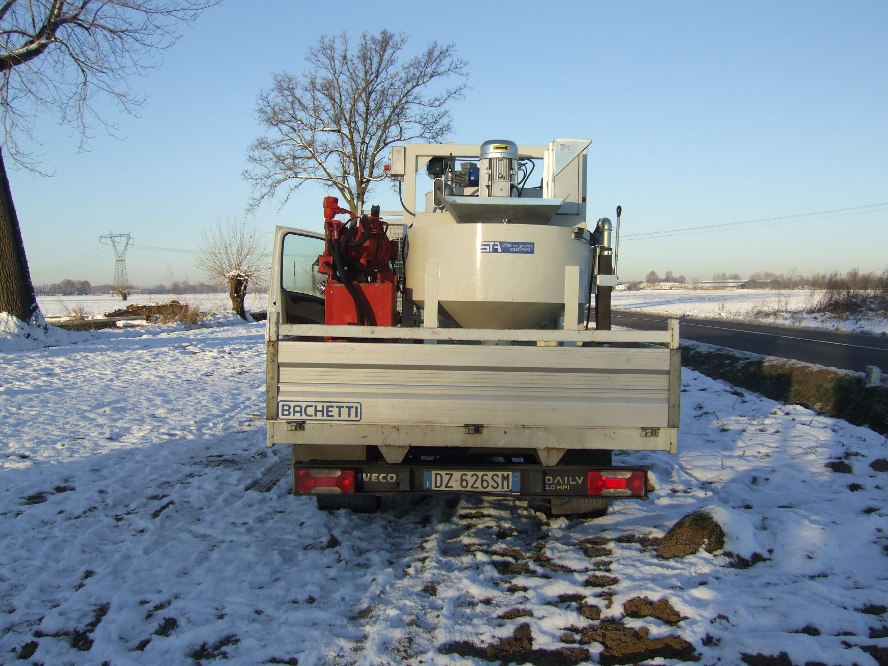 Un camion argentato con un container sul retro è parcheggiato nella neve