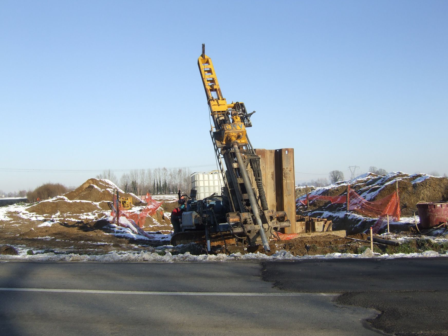 Un grande trapano giallo è appoggiato sul ciglio della strada