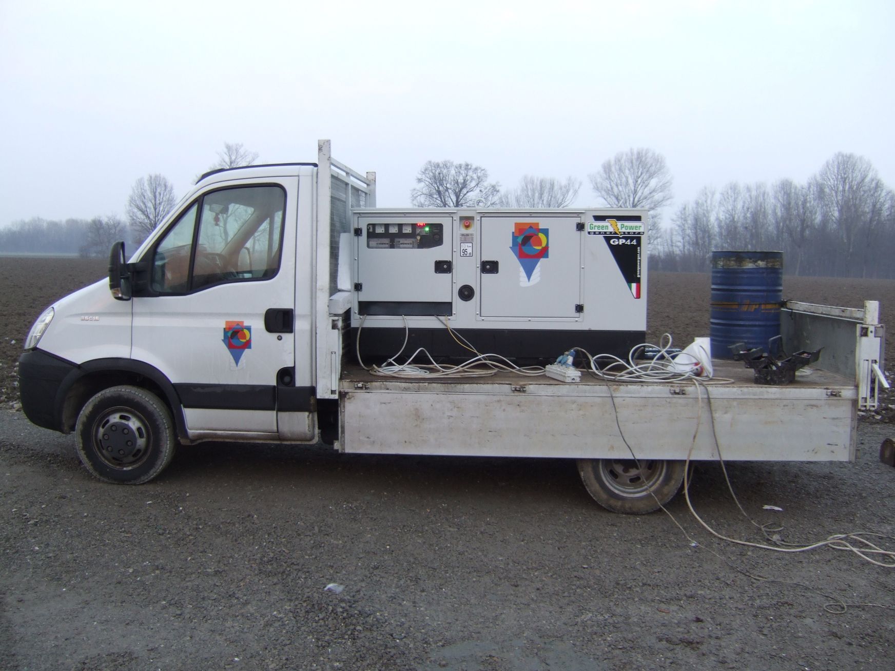 Un camion bianco con un generatore sul retro è parcheggiato sul ciglio della strada.