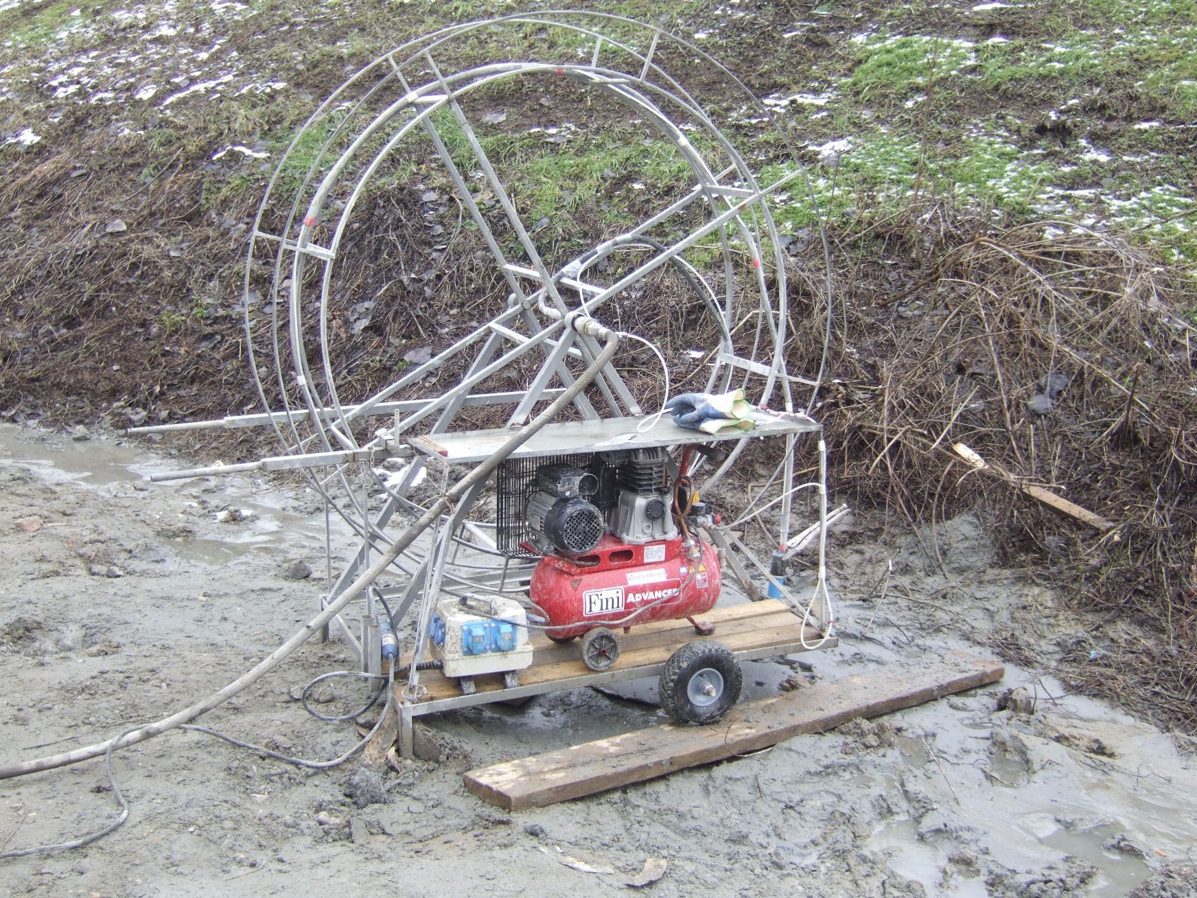 Un compressore d'aria rosso è posizionato sopra un rimorchio di legno.