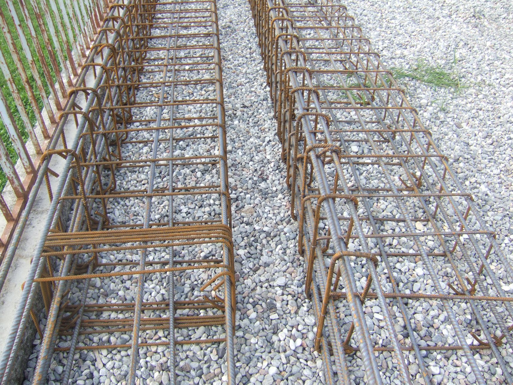 Un mucchio di sbarre di metallo appoggiate su un mucchio di ghiaia.