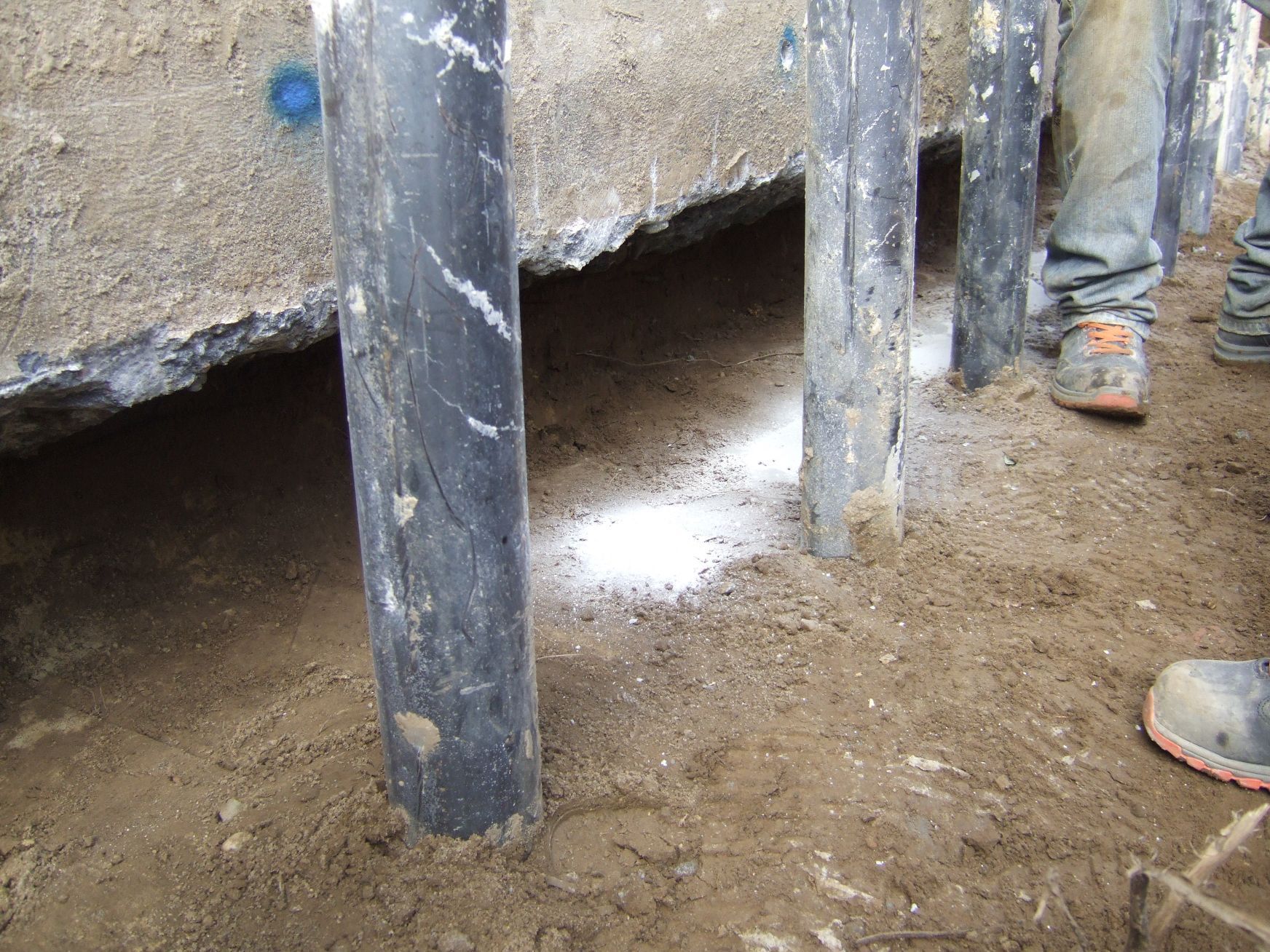 Una persona è in piedi accanto a un mucchio di terra e pilastri di cemento.