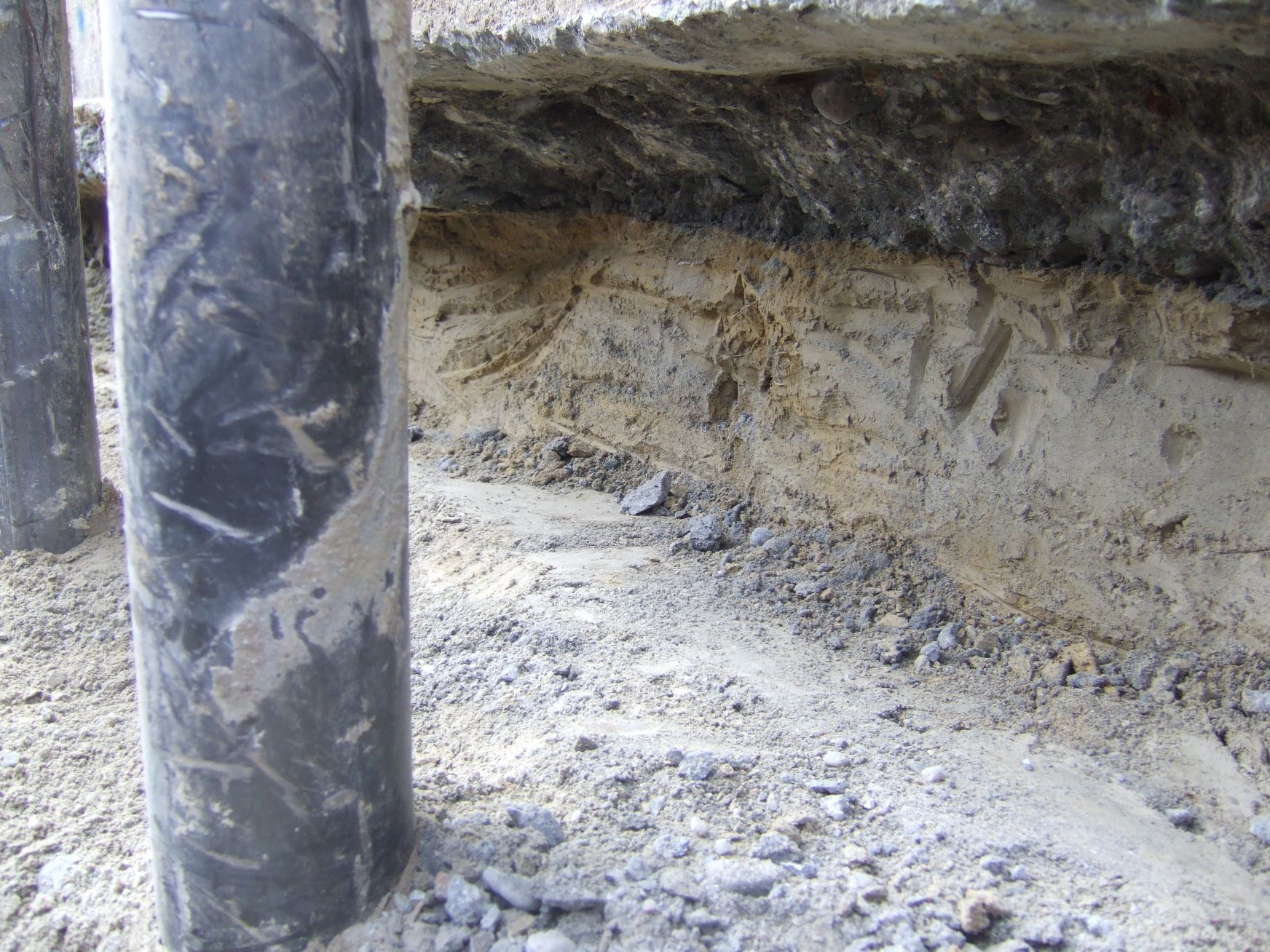 Un tubo nero è appoggiato nella terra accanto a una roccia.