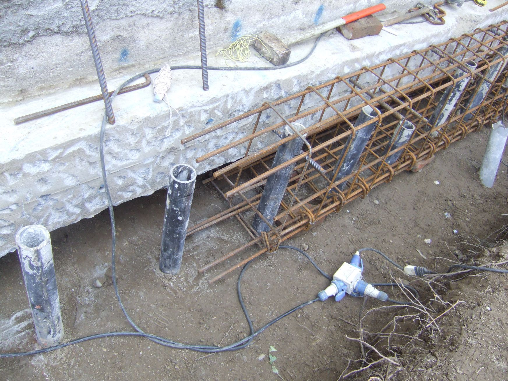 Un mucchio di fili è steso a terra, vicino a un muro di cemento.