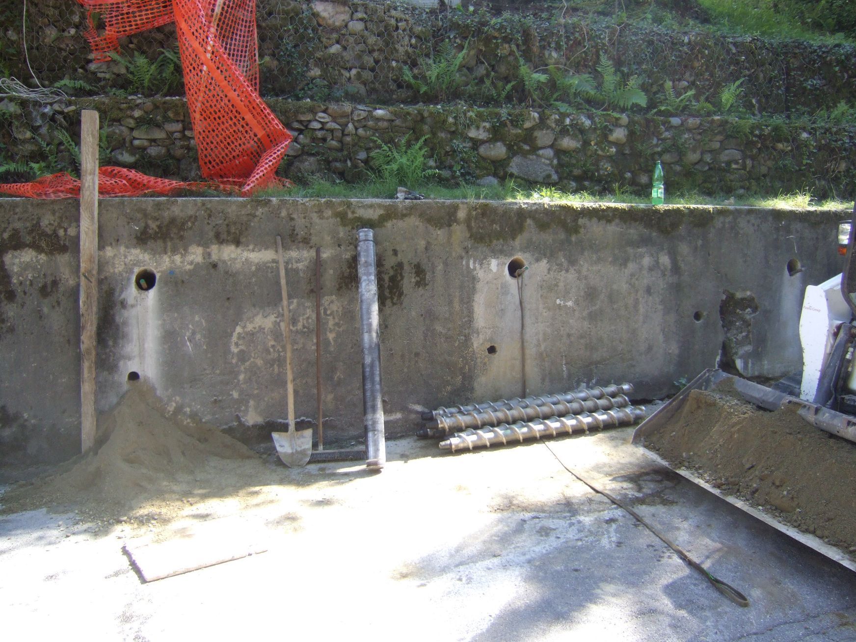 Un muro di cemento viene costruito accanto a una ruspa