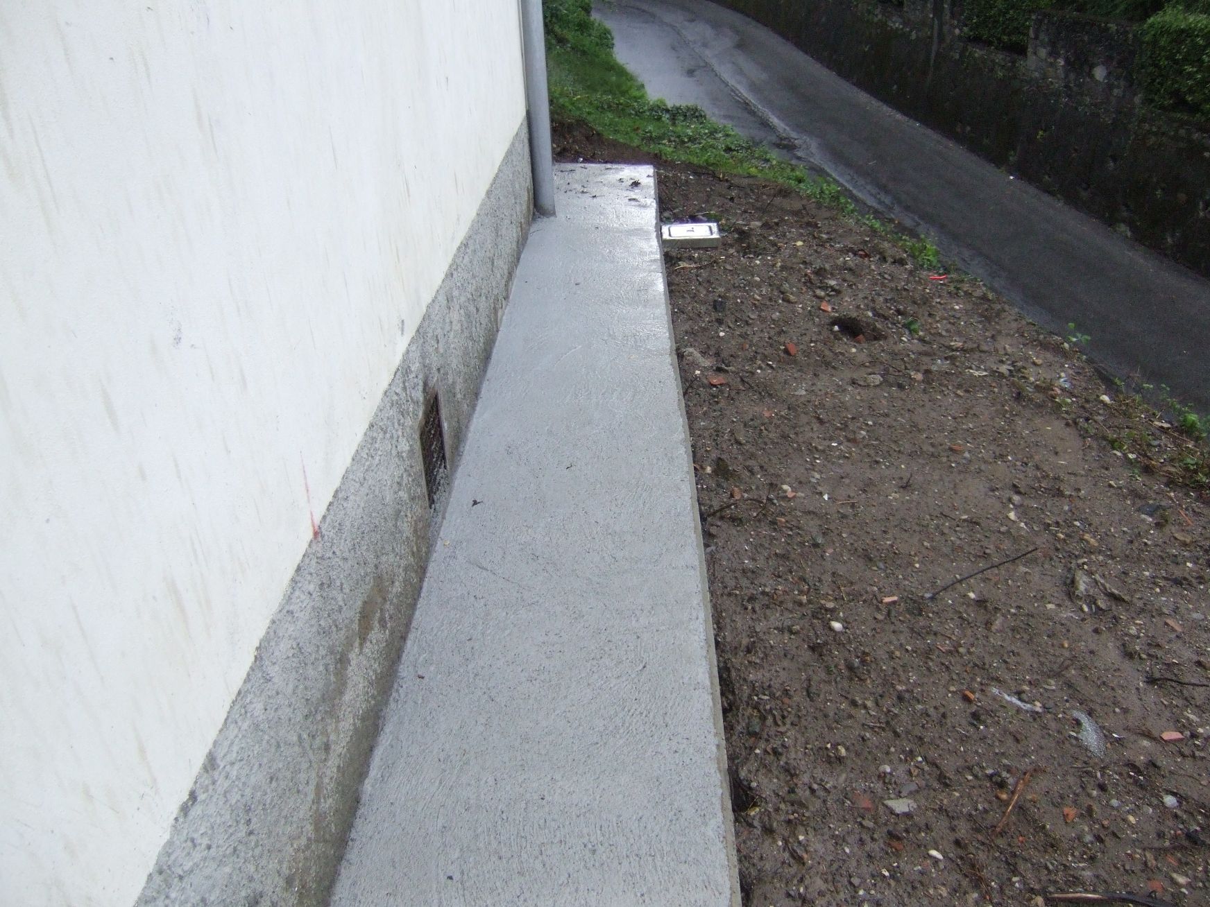 Un marciapiede accanto a un edificio bianco accanto a una strada