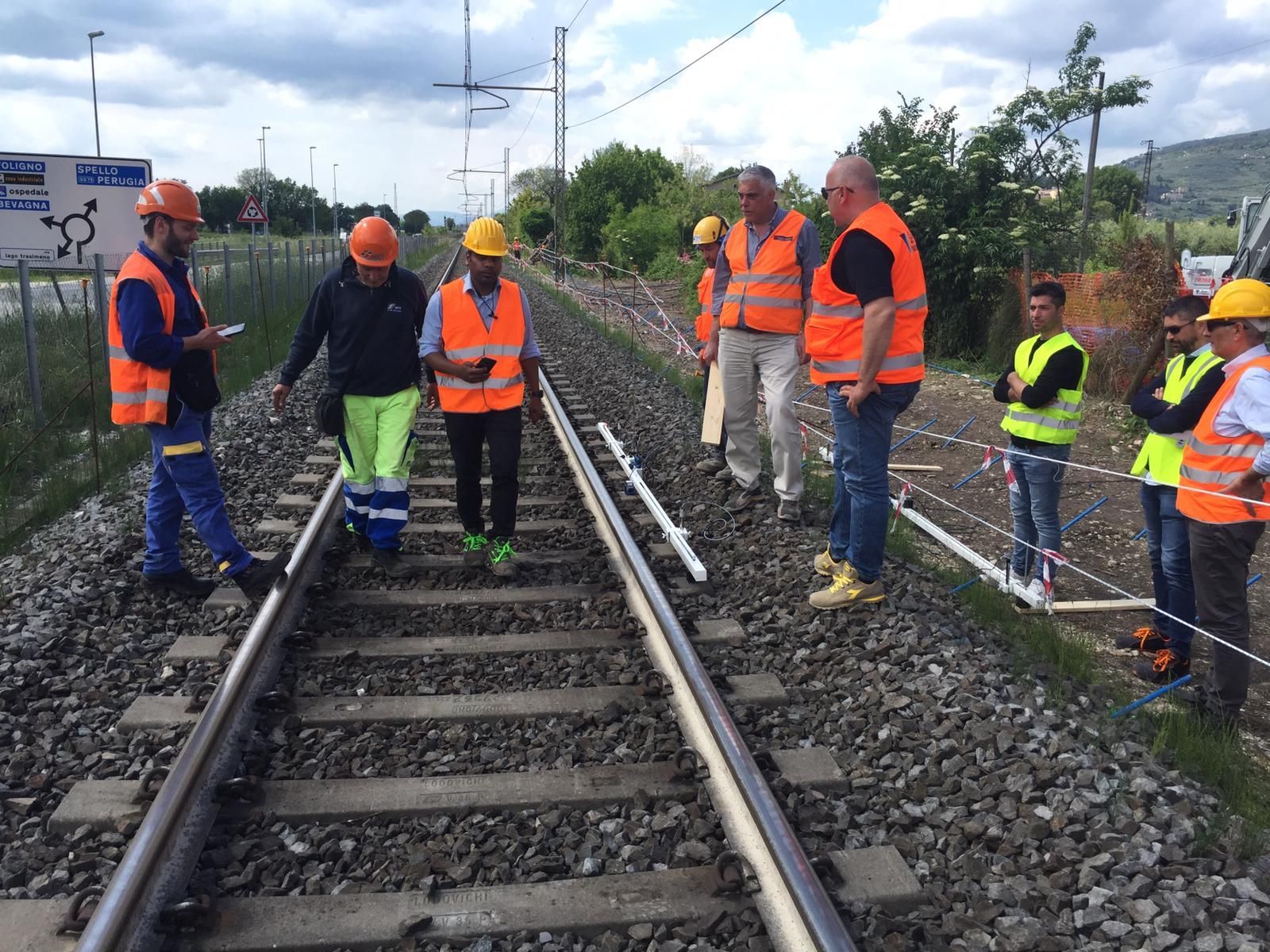 Un gruppo di operai edili è in piedi sui binari del treno