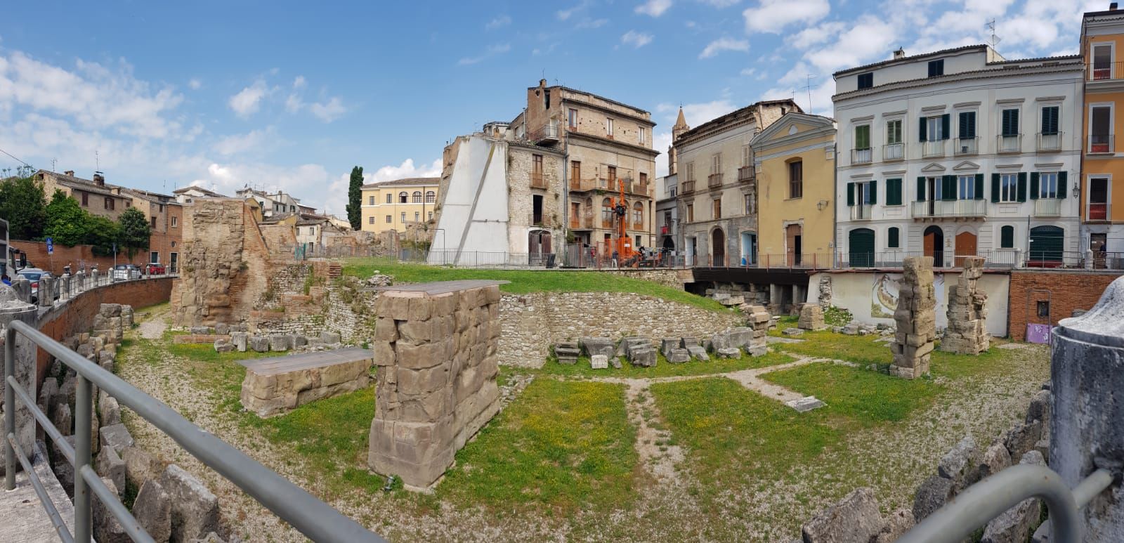 Una vista panoramica di una città con una recinzione in primo piano e degli edifici sullo sfondo.