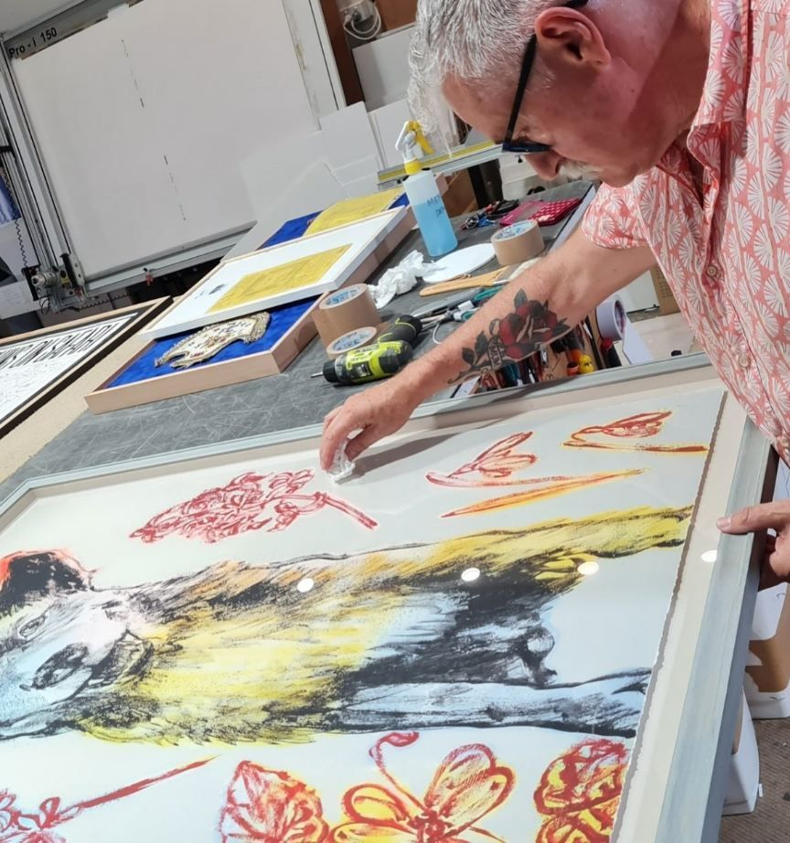 A Man is Cleaning a Painting — Next Level Picture Framing In Ballina, NSW