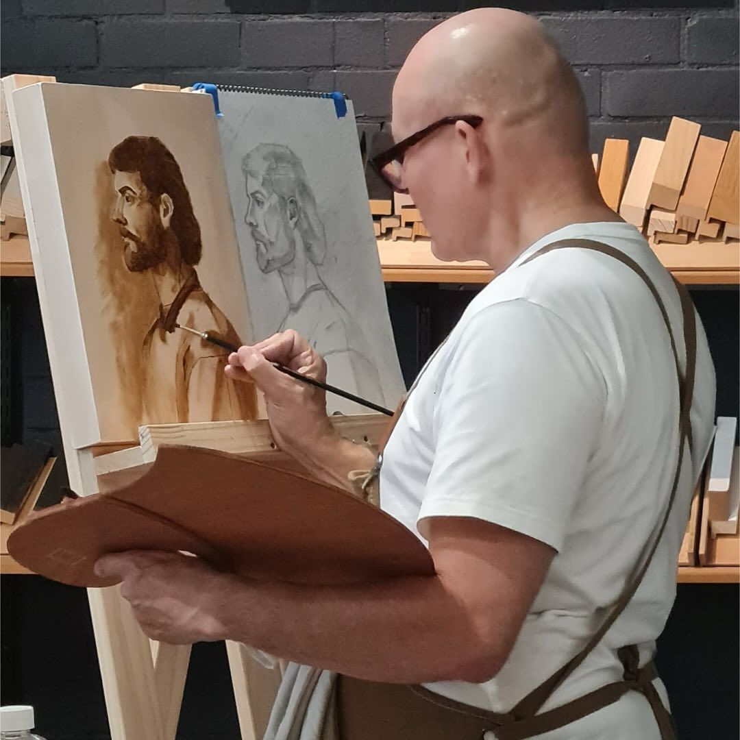 A Man is Painting a Portrait of a Man on an Easel — Next Level Picture Framing In Ballina, NSW