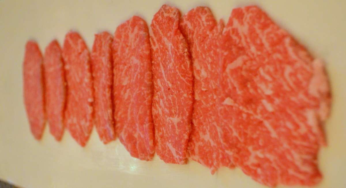 a row of red meat slices on a white surface