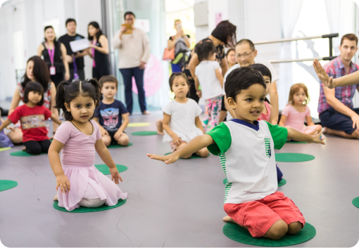 Image 4: A group of children are sitting on the floor in a dance studio.