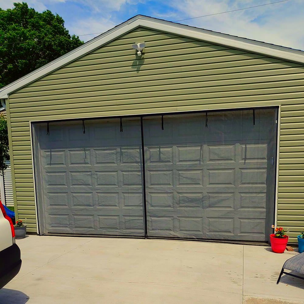 A car is parked in front of a green garage door