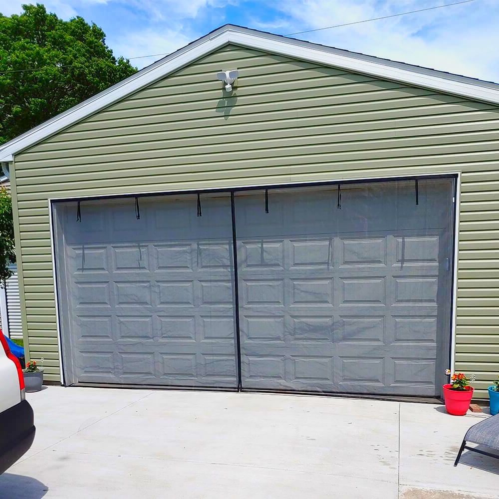 A car is parked in front of a large garage door.