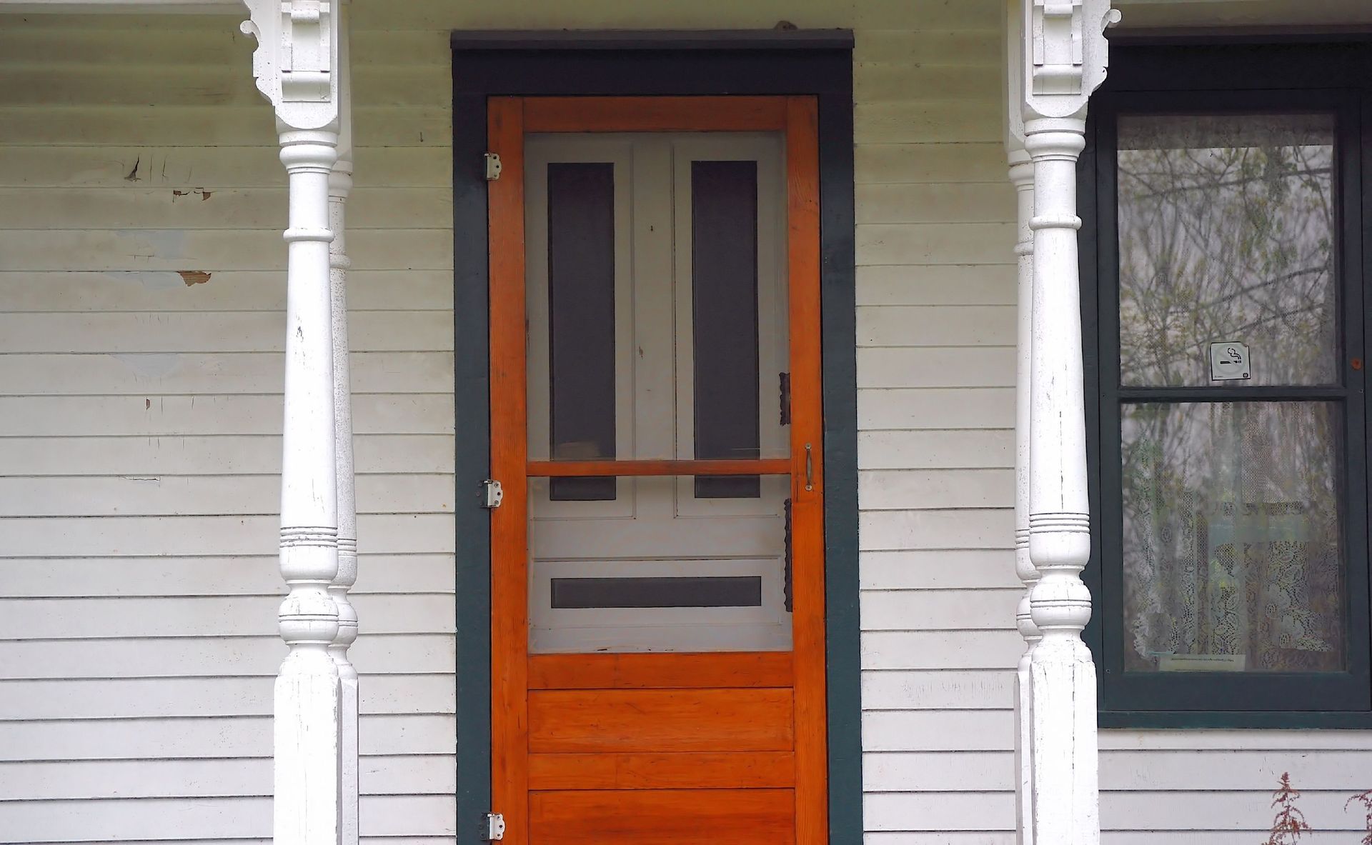 A white house with an orange screen door