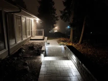 Welcoming front entrance with landscape lighting in Burnaby. This outdoor lighting design uses a combination of path lights and soft downlights to illuminate the entryway, enhancing curb appeal and safety for this home near Lougheed Town Centre. Keywords: Burnaby landscape lighting, professional installation, garden lighting, exterior illumination, low voltage solutions, property value, safe access.
