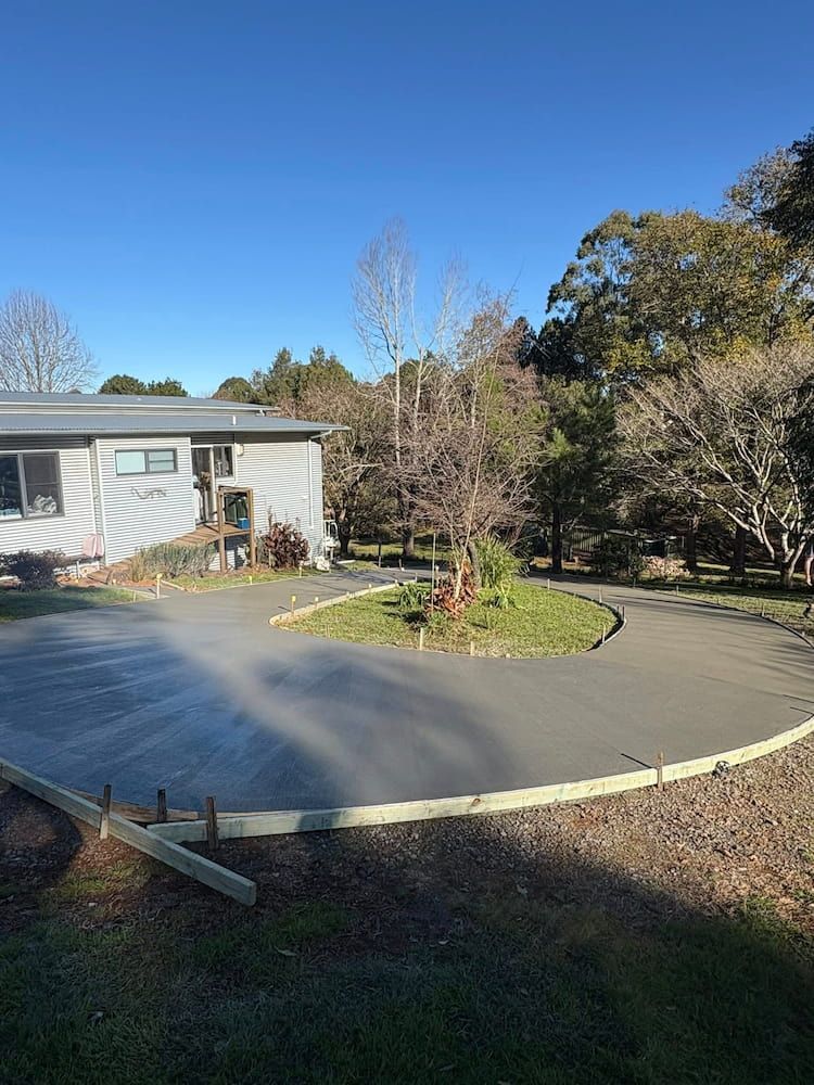 Newly Poured Concrete Driveway Curves in Front of a Modern House, Surrounded by Trees — JDC Concreting in Lismore, NSW