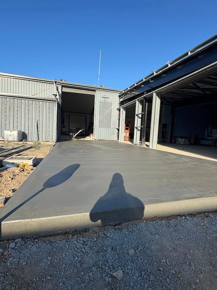 Newly Poured Concrete Slab in Front of Metal Buildings, Sunny Day — JDC Concreting in Ballina, NSW