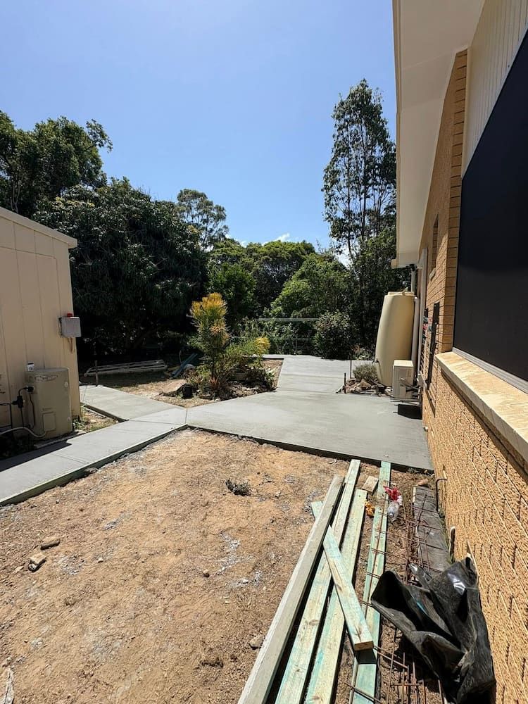 Exterior View With Newly Poured Concrete Pathways, Exposed Dirt, and a Building — JDC Concreting in Grafton, NSW