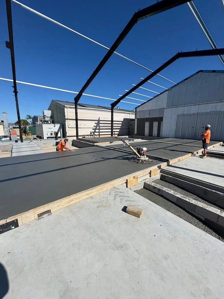 Construction Workers Smoothing Wet Concrete Floor Under a Metal Beam Structure — JDC Concreting in Grafton, NSW