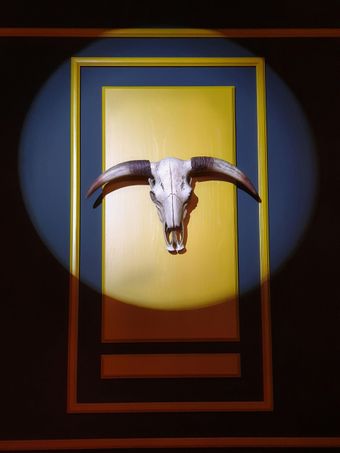 A bull skull with long horns mounted in a gold-framed blue-and-gold panel