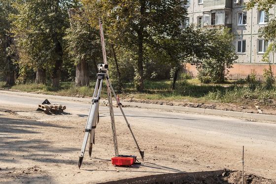 a tripod sitting on the side of a road next to a red bucket