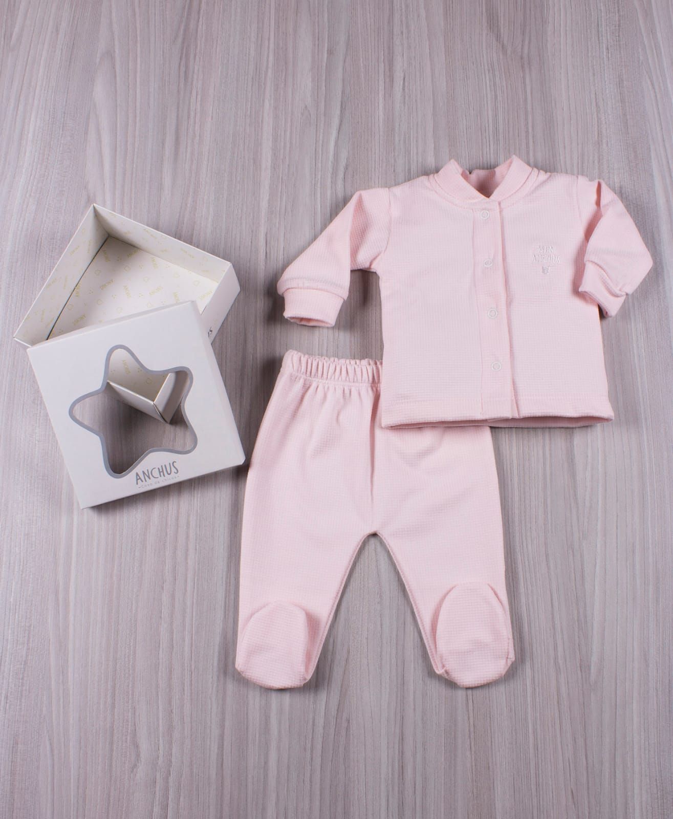Conjunto de bebé a cuadros color menta con pantalón a juego junto a una tarjeta doblada sobre una superficie de madera.