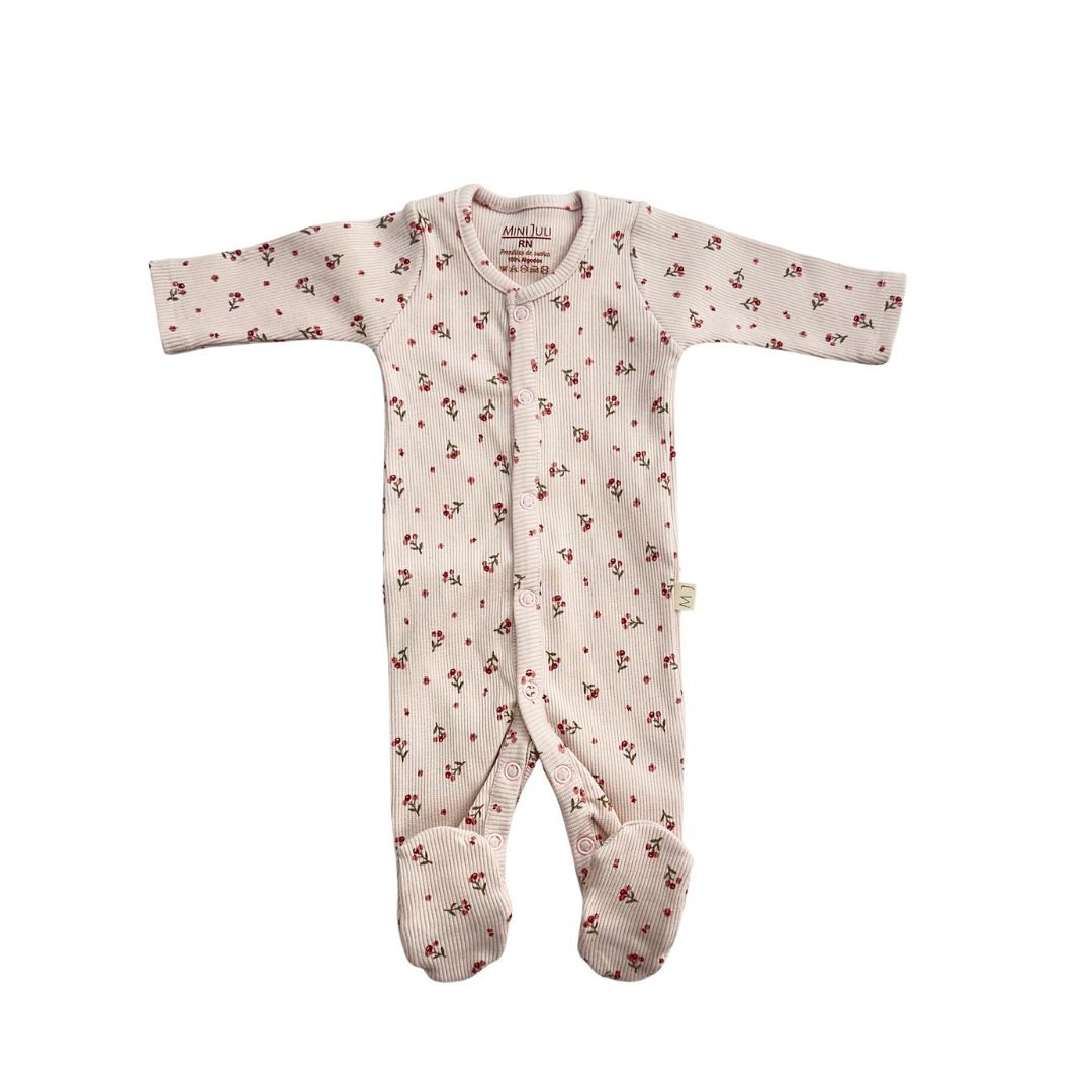 Body de bebé rosa claro con estampado floral, mangas largas y pies, extendido sobre un fondo blanco.