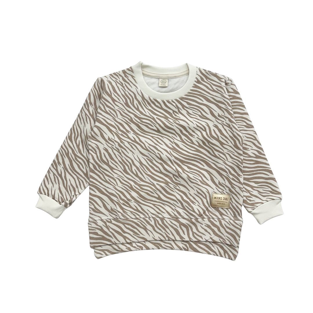 Sudadera infantil de manga larga color beige con estampado de cebra, ribete blanco y un pequeño parche de oso.
