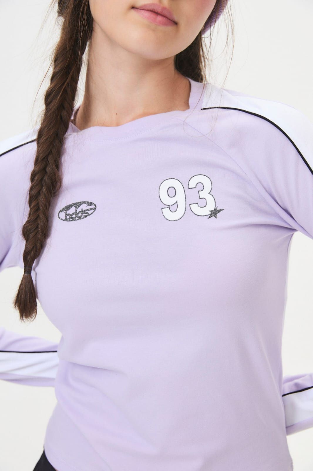 Mujer con una camisa de manga larga de color lila claro con el número “93” en el pecho.