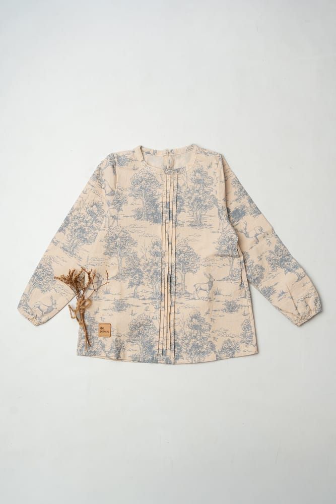 Camisa de manga larga color crema con botones, estampado floral azul y una mancha marrón
